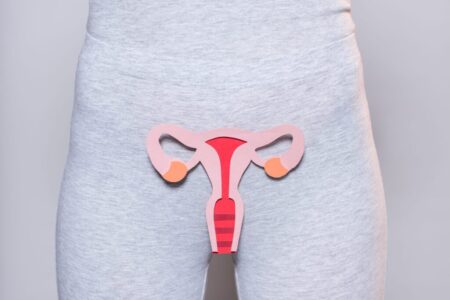 partial view of woman with paper made female reproductive system on grey background