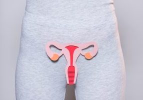 partial view of woman with paper made female reproductive system on grey background